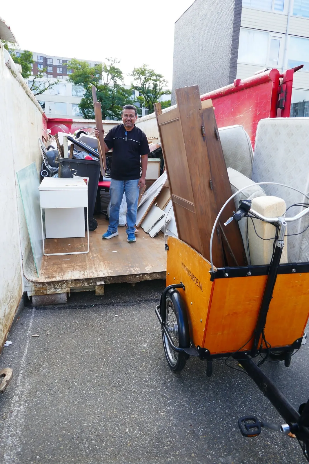 Een steekwagen met grofvuil wordt naar de container gebracht.