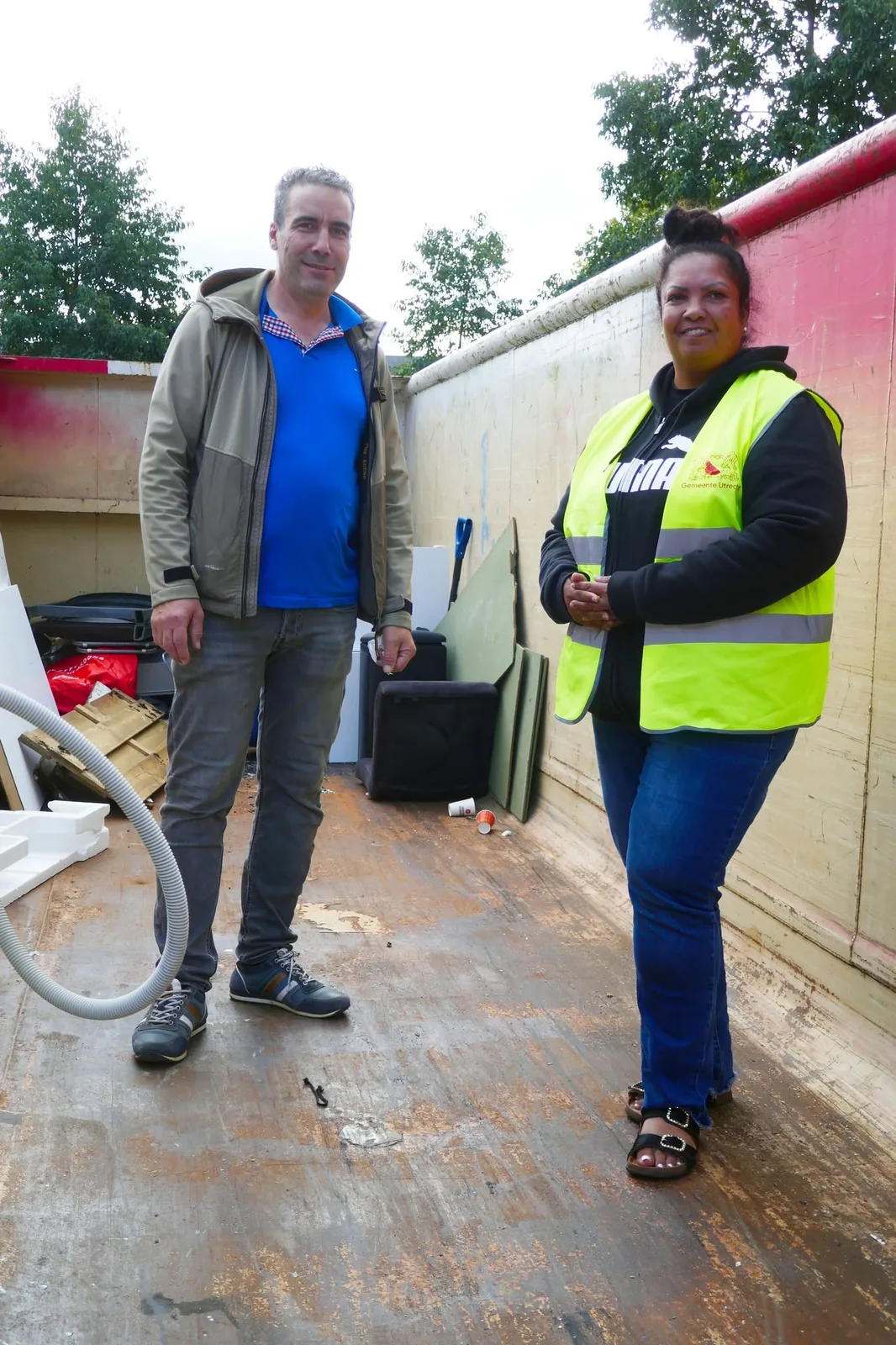 Een vrijwilliger helpt grofvuil bij de container verzamelen.