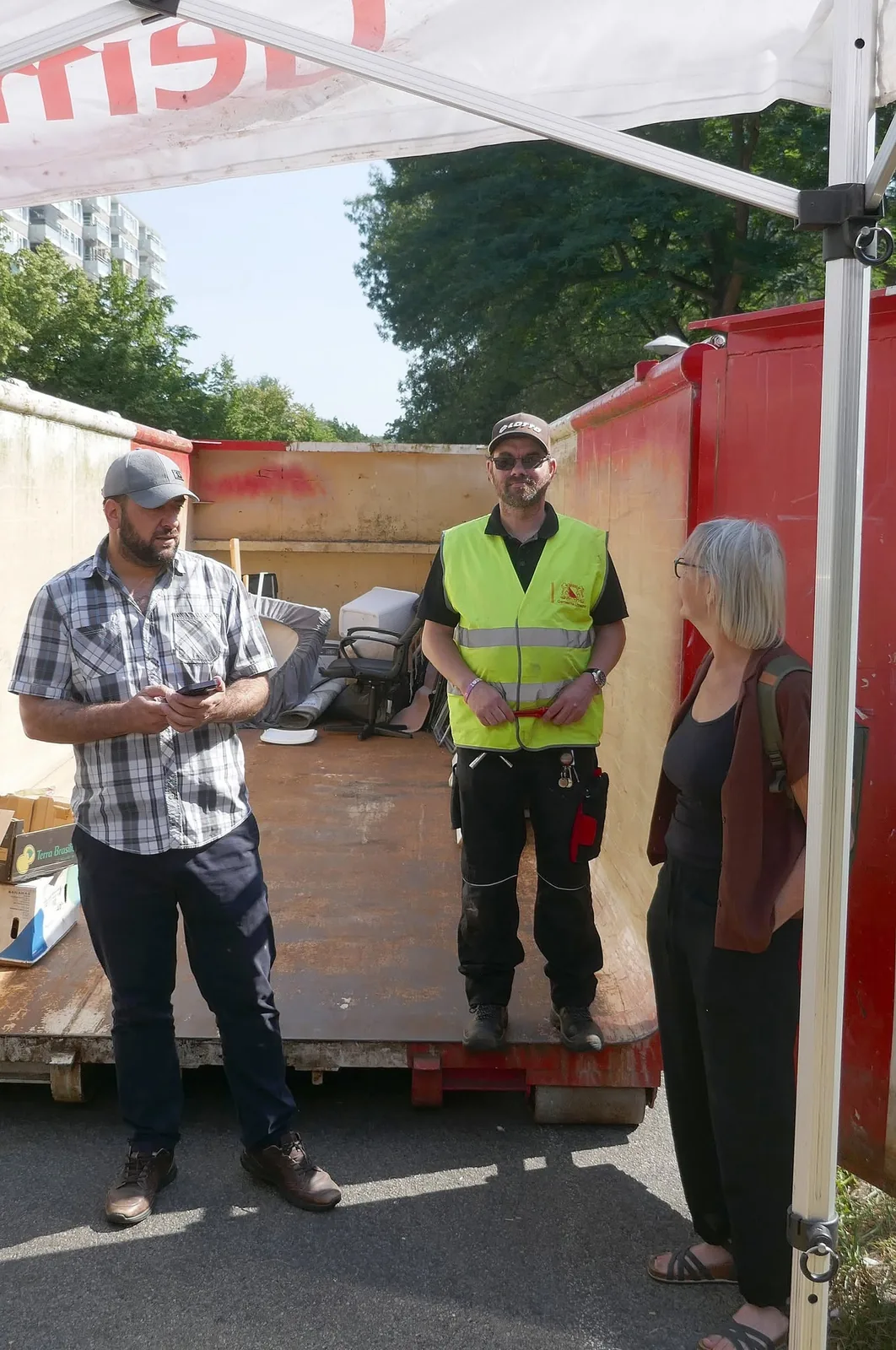 Bewoners en vrijwilligers overleggen bij de container.